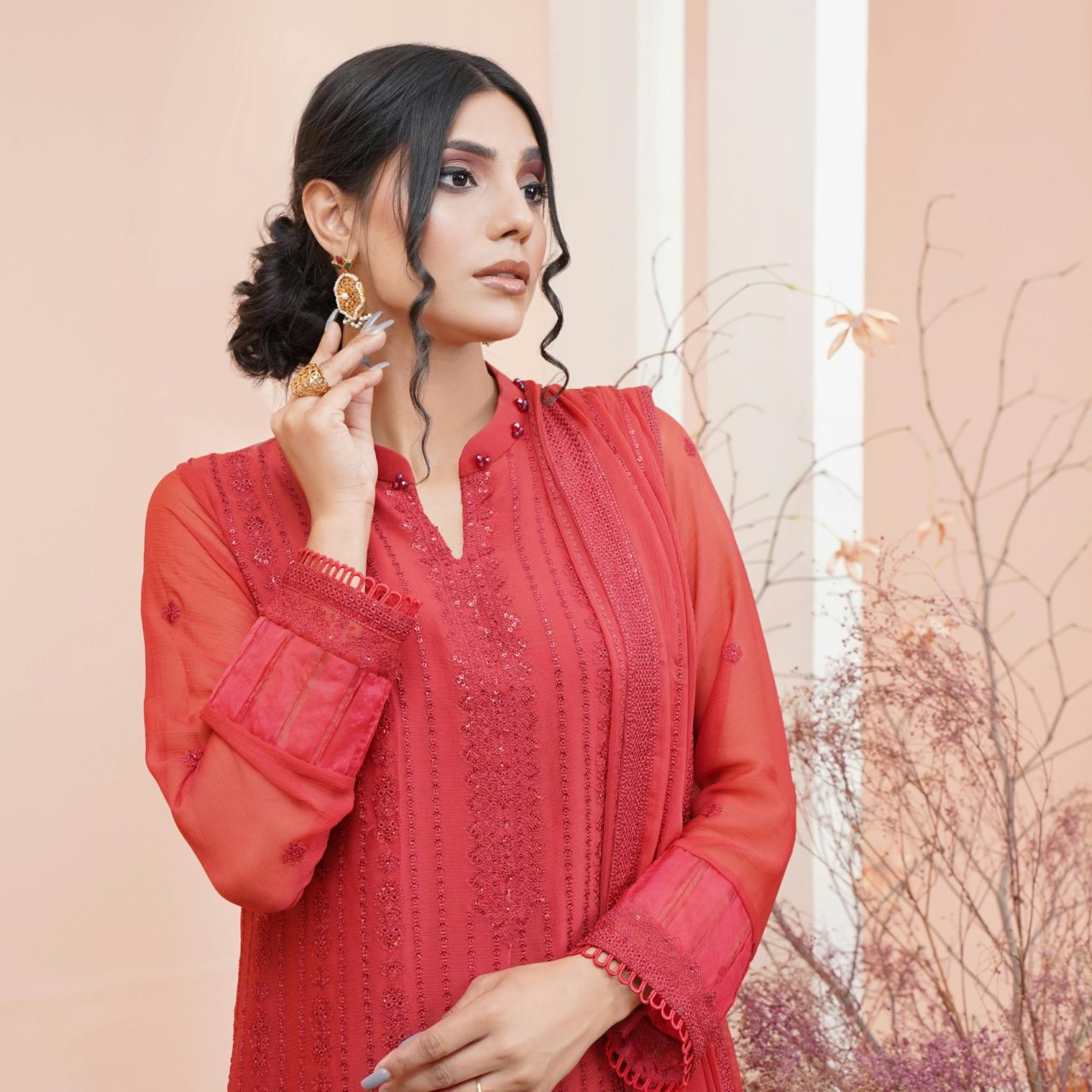 Woman in elegant traditional red dress posing indoors with an artistic touch.